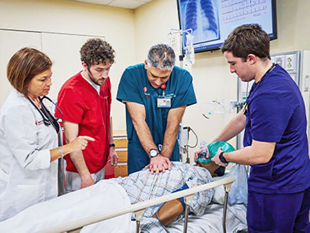 Medical school students practicing on a manikin.